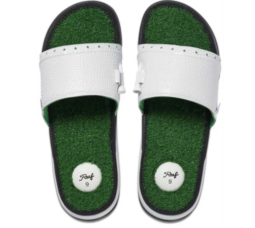A pair of funny flip-flop style shoes. The soles of the shoes are covered in fake grass. on the heel part of each sole is a white rubber circle that looks like a golf ball. The thick white strap that covers the top of the foot has holes in it for holding golf tees.